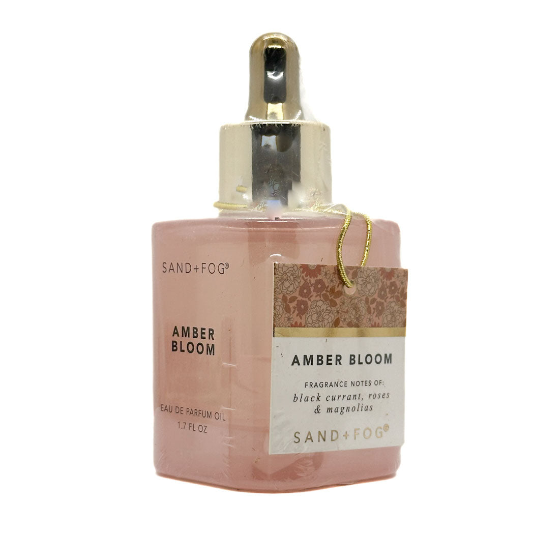 Pink perfume oil bottle with gold cap labeled 'Amber Bloom' by Sand + Fog on a white background