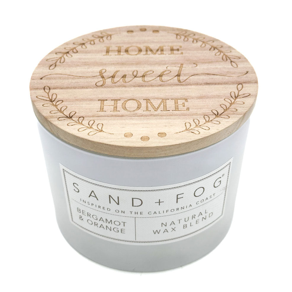 Bergamot & Orange candle with wooden lid featuring 'Home Sweet Home' text, brand 'Sand + Fog' visible.