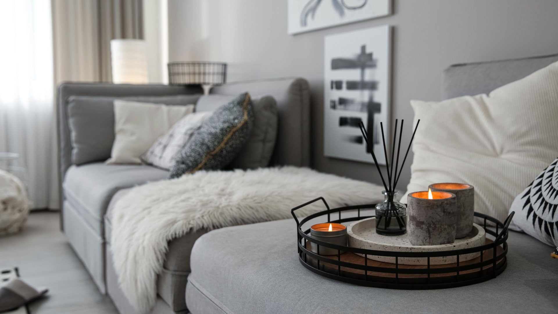 Cozy living room with a gray sofa, decorative pillows, and a coffee table with candles.