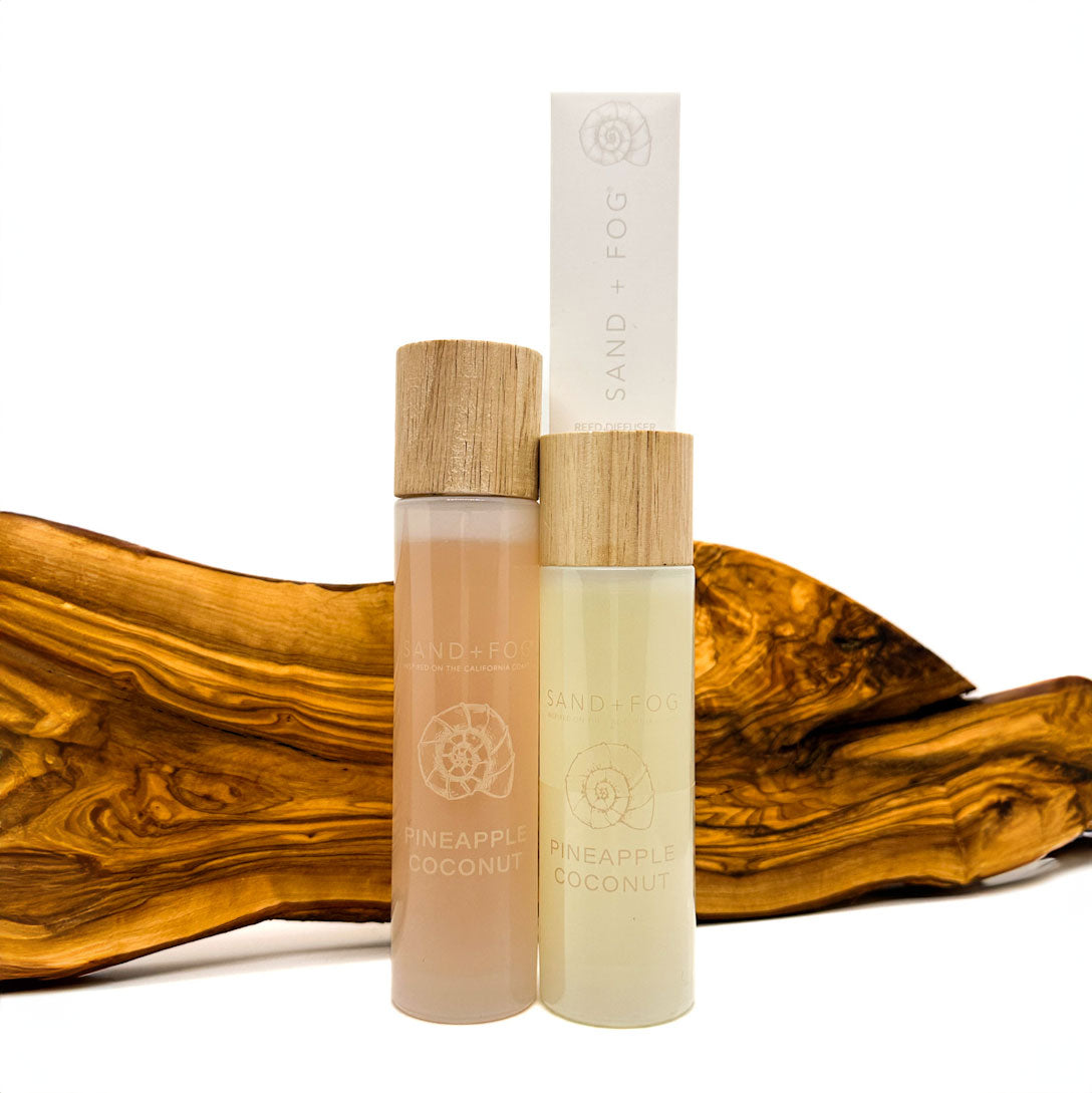 Two bottles of Pineapple Coconut Room Spray & Reed Diffuser fragrance with wooden caps on a white background