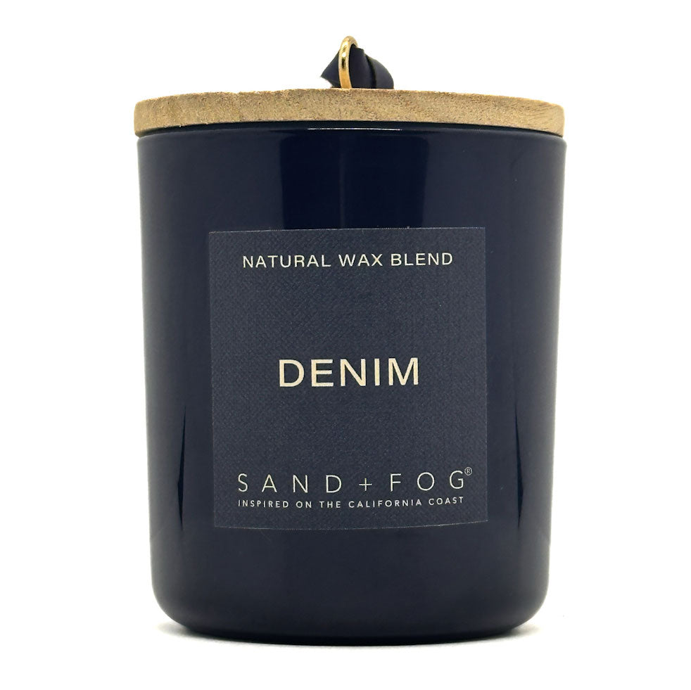 Navy candle with 'Denim' label and 'Sand + Fog' branding on a white background
