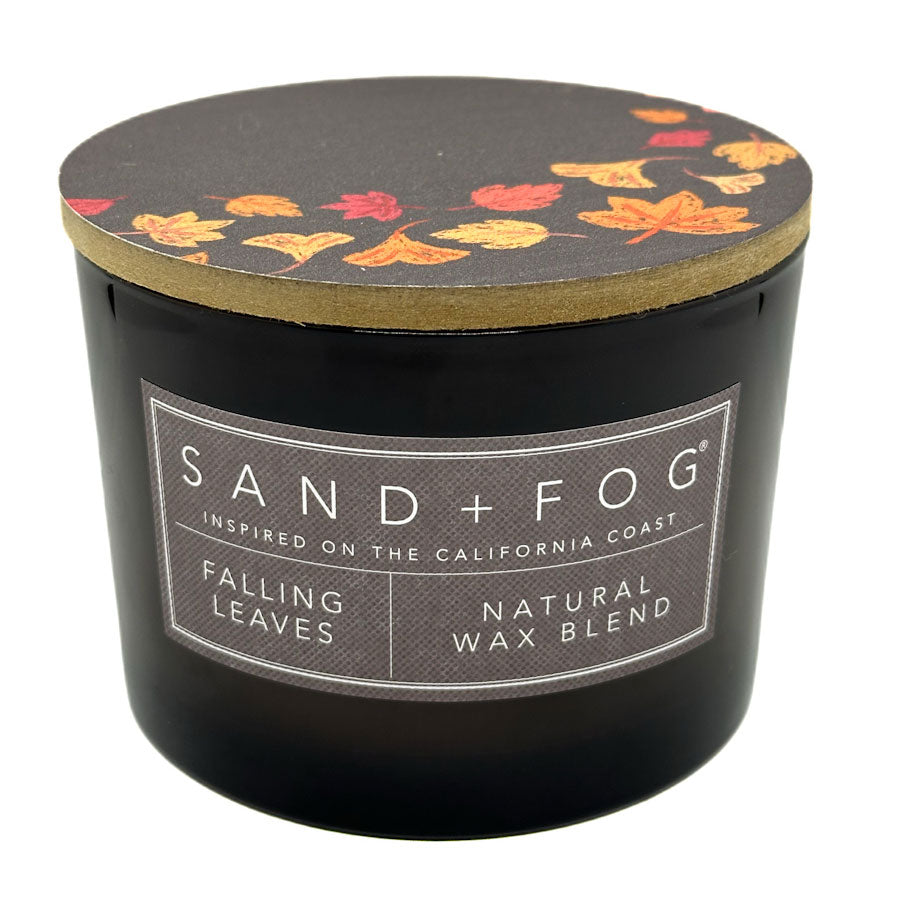Falling Leaves black candle with 'Sand + Fog' label and leaf pattern on lid against a white background