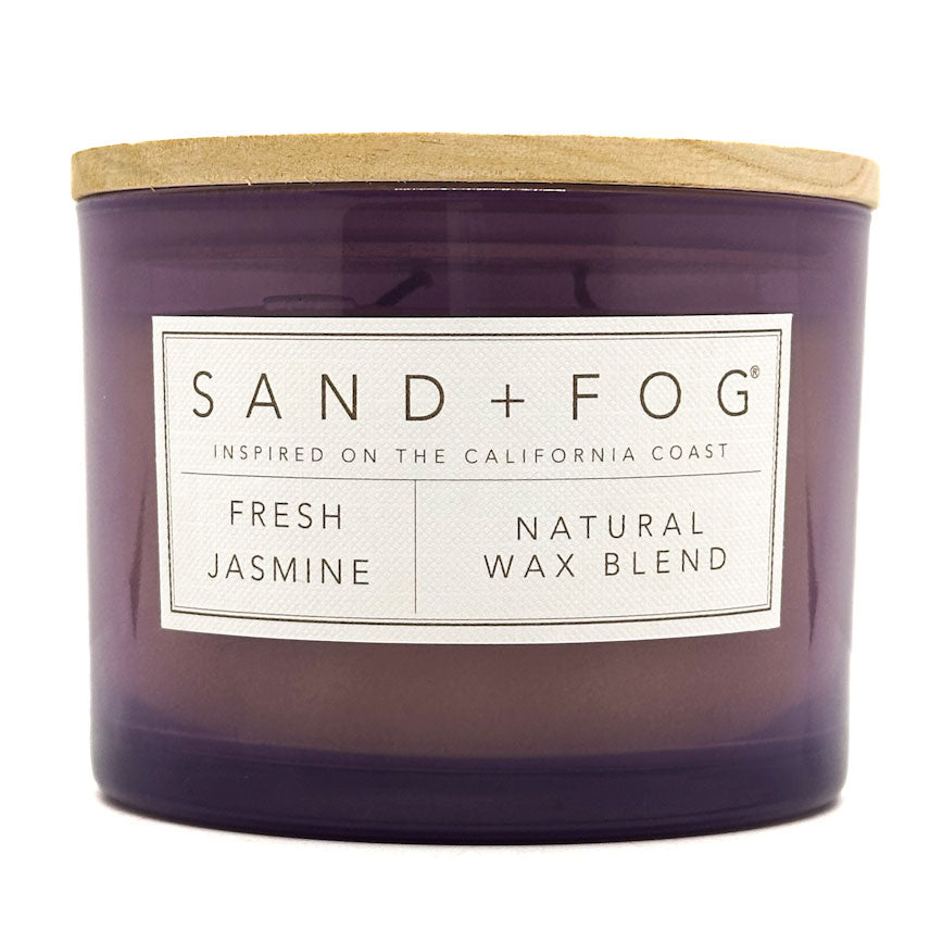Purple SAND + FOG candle with a wooden lid and 'Sand + Fog' label on a white background