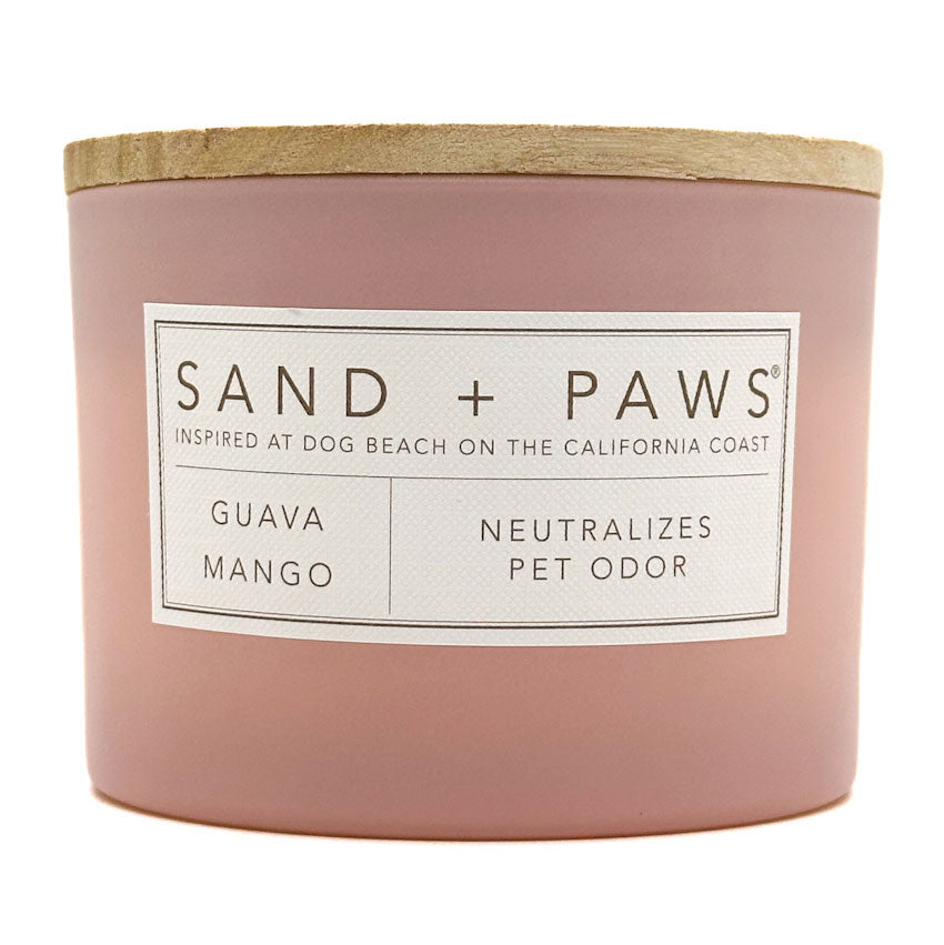 Guava Mango Pink candle labeled 'Sand + Paws' with a wooden lid on a white background