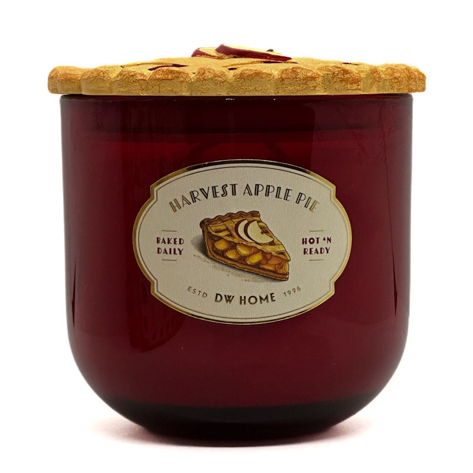 A large red glass jar candle with a matching glass lid, featuring a vintage-style label that reads 'Harvest Apple Pie' with an illustration of an apple pie slice. The candle is photographed on a clean white background.