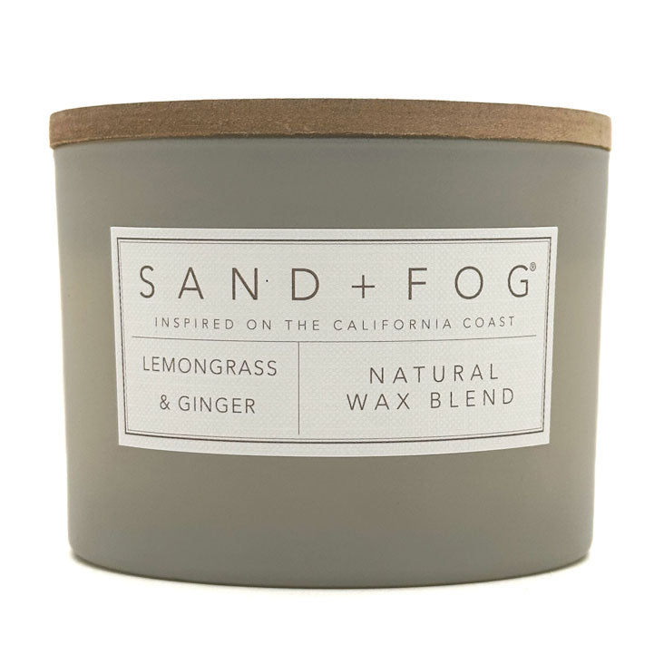 Gray Lemongrass & Ginger candle with a wooden lid labeled 'Sand + Fog' on a white background