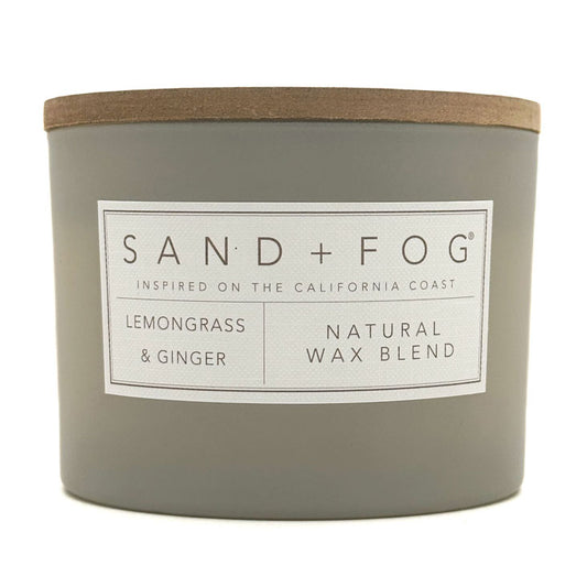Gray Lemongrass & Ginger candle with a wooden lid labeled 'Sand + Fog' on a white background