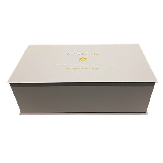 A rectangular presentation box for 'NINETY SIX' fragrances, featuring a light beige lid with gold foil lettering and a dark gray base, photographed on a clean white background.
