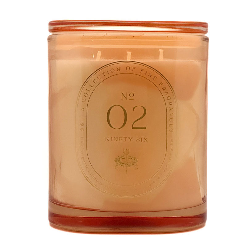 An amber glass jar candle with a matching amber lid, filled with pale peach wax. The front features a circular embossed label reading 'No 02 Ninety Six' and 'A Collection of Fine Fragrances'.