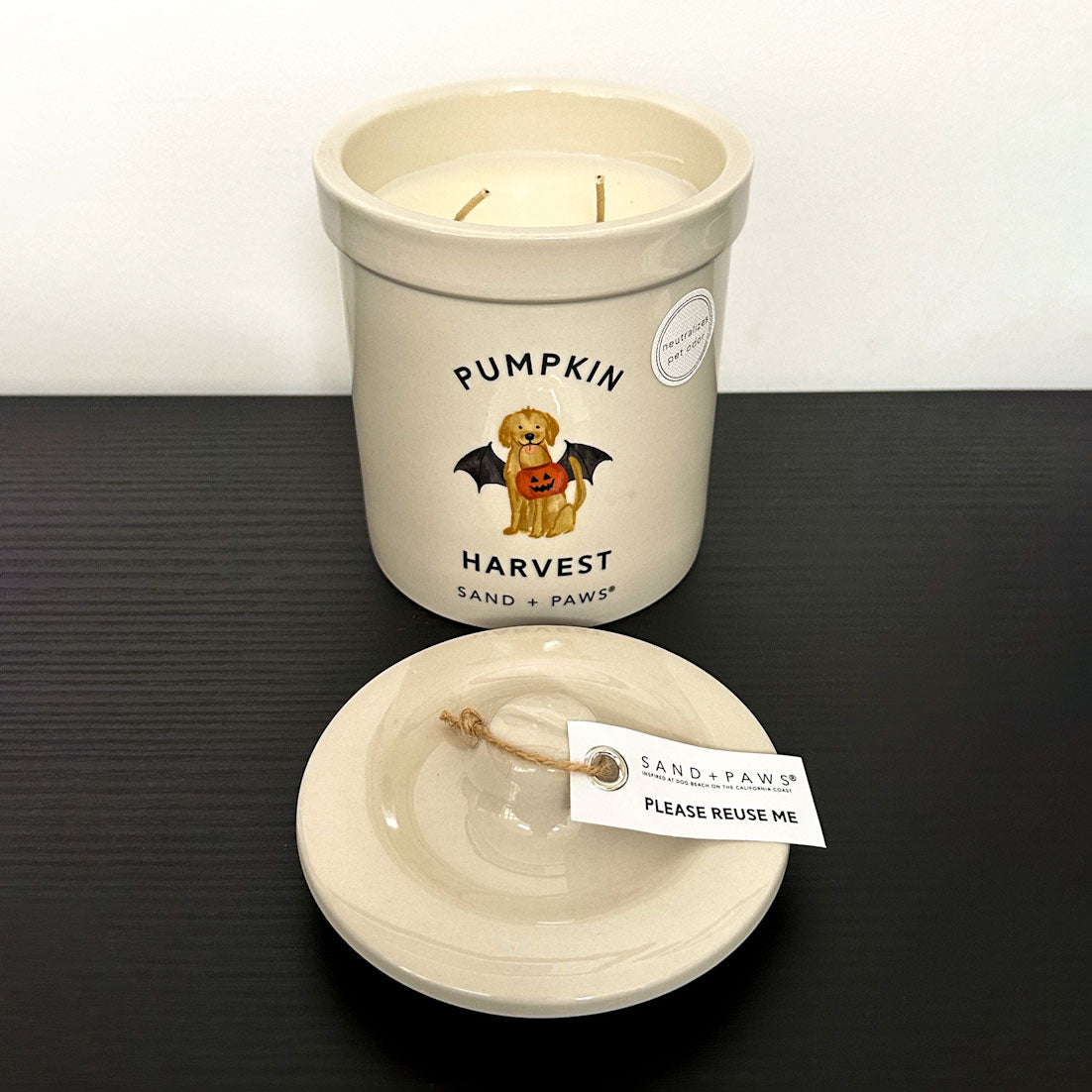 Candle with 'Pumpkin Harvest' label and lid on a dark surface