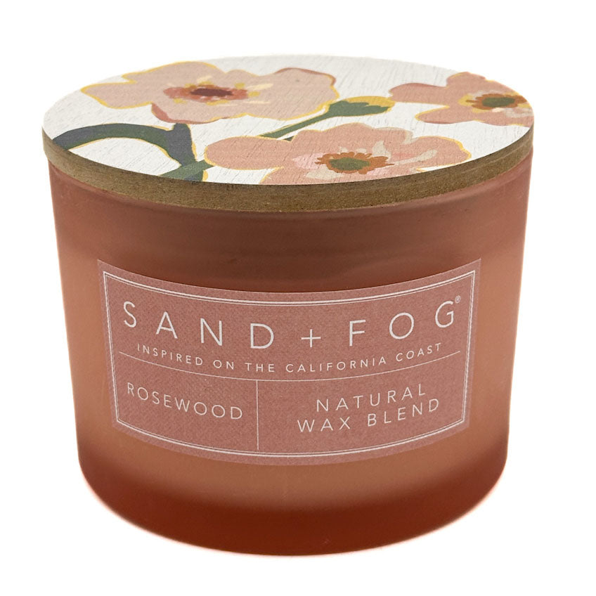 Rosewood candle with floral lid and 'Sand + Fog' label on a white background