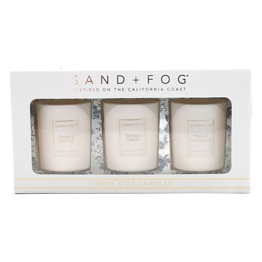 Three candles in a box with 'Sand + Fog' branding on a white background