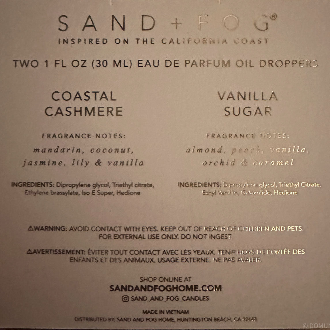 label of a Sand + Fog perfume oil dropper set, showing the Coastal Cashmere and Vanilla Sugar scents with notes, ingredients, and website information on a beige background.