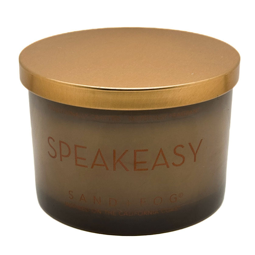Speakeasy candle in amber glass with gold lid on a white background