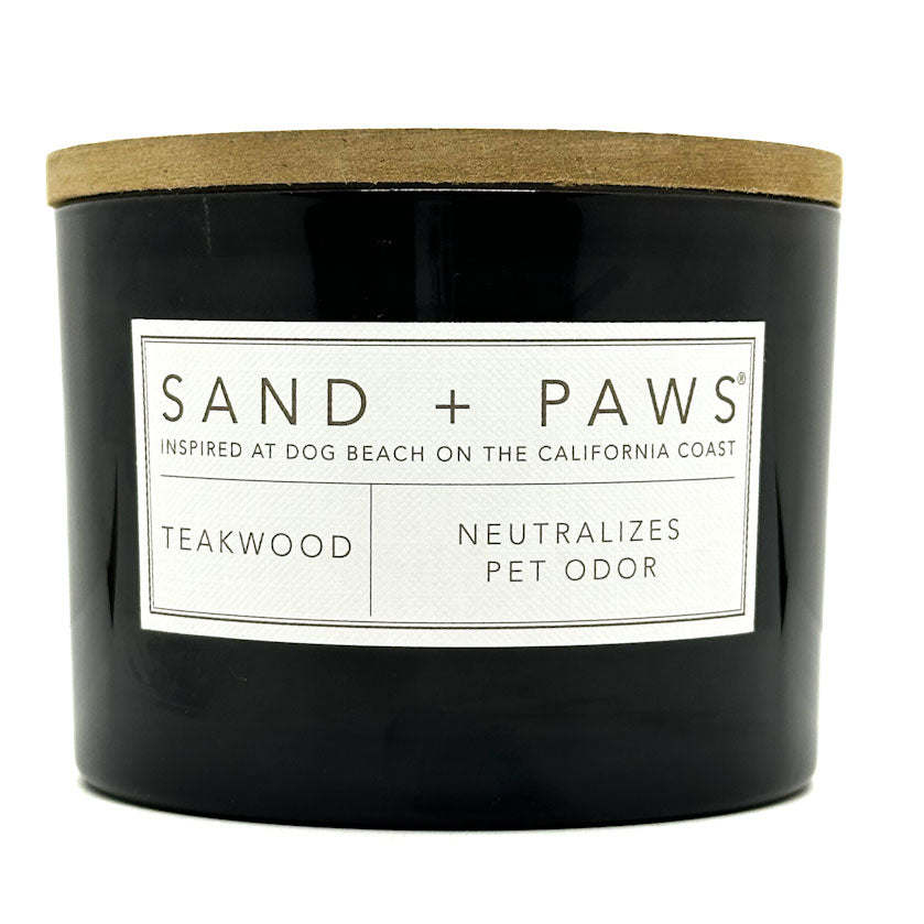 Teakwood black candle with a wooden lid and 'Sand + Paws' label on a white background