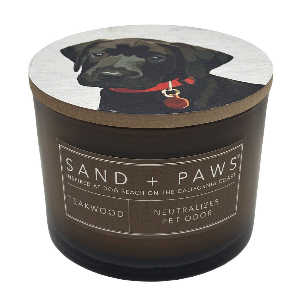 Teakwood candle with a dog illustration on the lid and 'Sand + Paws' branding.