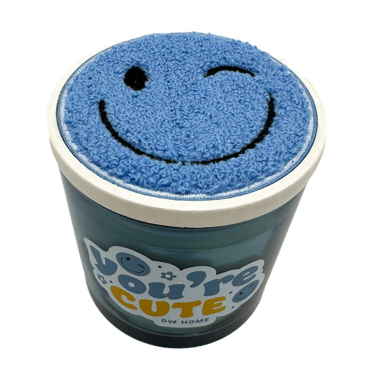 Blue candle by DW HOME with smiley face on lid and 'You're Cute' text on a white background