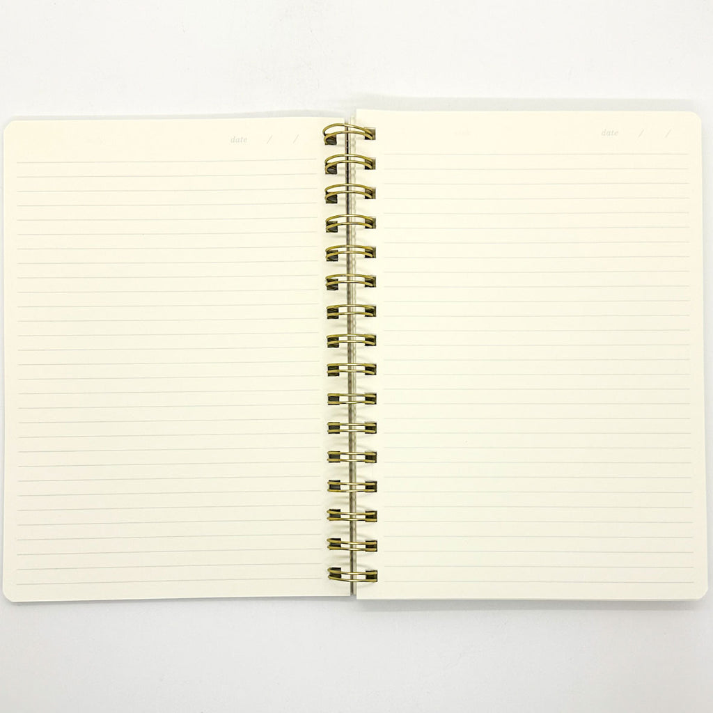 Open notebook with lined pages and gold spiral binding on a white background