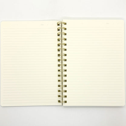 Open notebook with lined pages and gold spiral binding on a white background