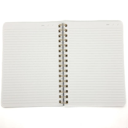 An open spiral-bound lined notebook with white pages and a silver metal coil binding, photographed on a plain white background.