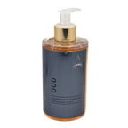 A bottle of Alchimia Oud Fine Liquid Soap, featuring a dark slate blue label, a metallic gold pump collar, and a clear pump dispenser, filled with amber-coloured liquid, set against a plain white background.