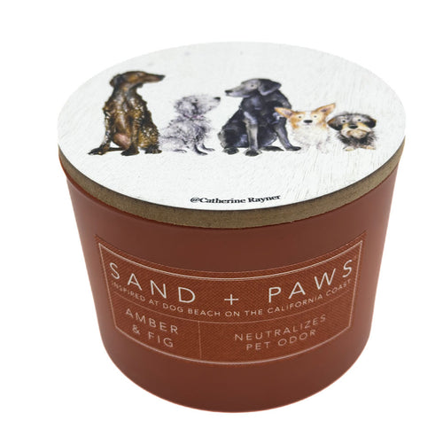 Amber & Fig Candle with dog illustrations on the lid and 'Sand + Paws' branding on the container.