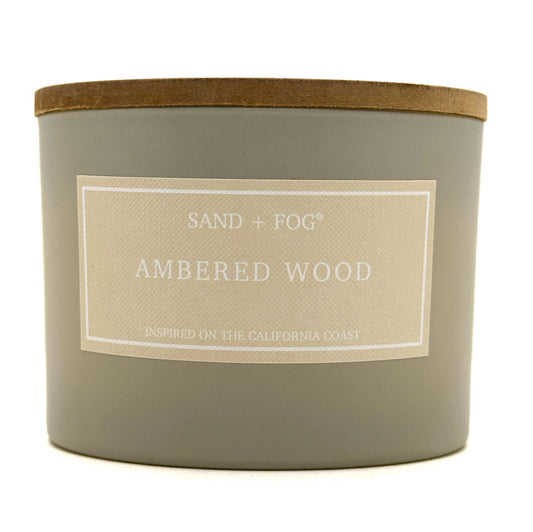 Ambered Wood Candle with 'Sand + Fog' label on a white background