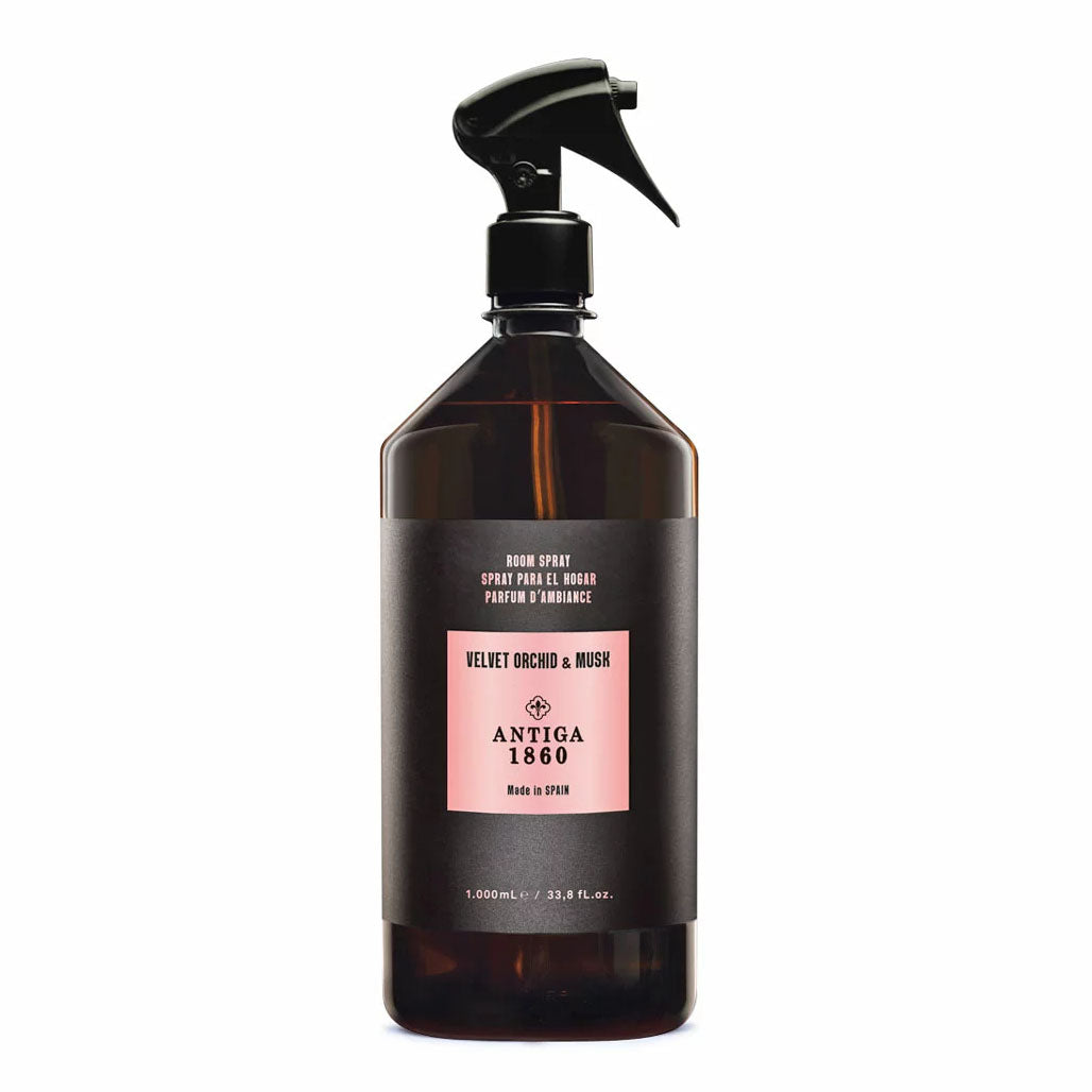 A dark amber spray bottle with a black trigger sprayer and a black label featuring a pink rectangular panel. The label reads 'VELVET ORCHID & MUSK' and 'ANTIGA 1860'.