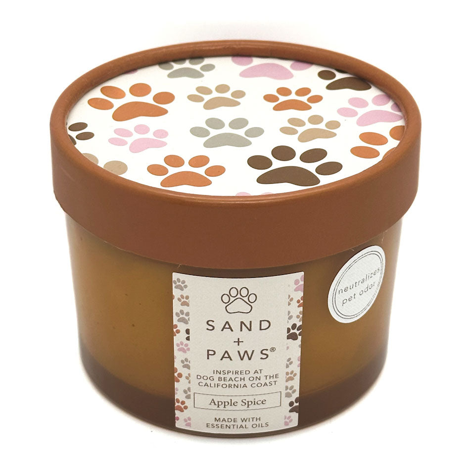 Apple Spice candle with paw print design on lid and 'Sand + Paws' label on container.