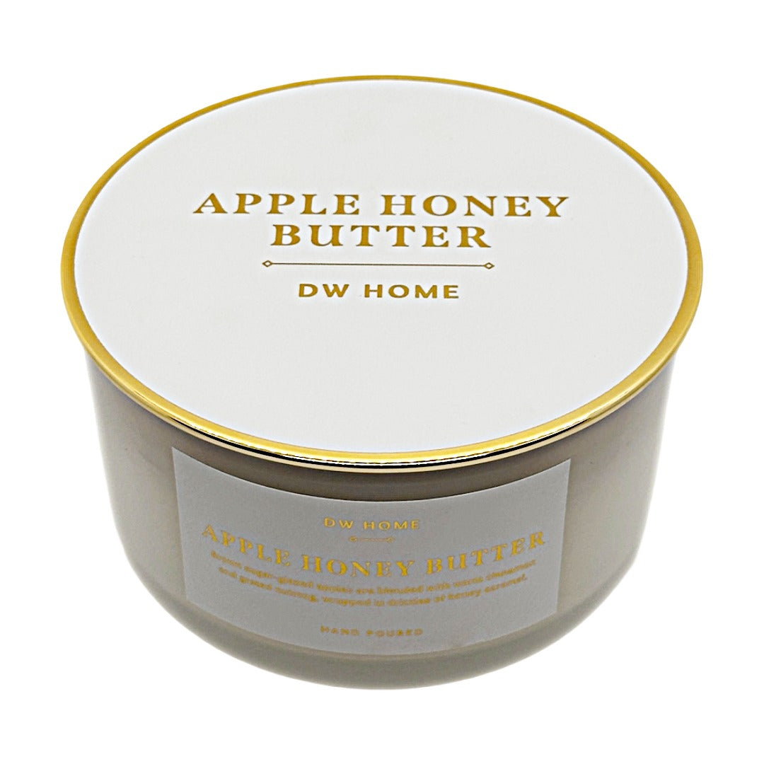 A round jar candle with a white lid and a white front label, both printed with gold text reading 'APPLE HONEY BUTTER' and 'DW HOME'. The candle is photographed on a clean white background.