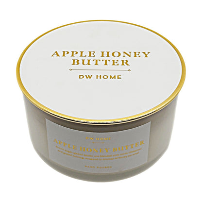 A round jar candle with a white lid and a white front label, both printed with gold text reading 'APPLE HONEY BUTTER' and 'DW HOME'. The candle is photographed on a clean white background.