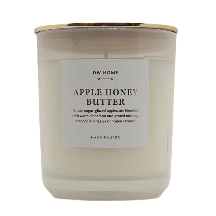 A single-wick candle in a frosted glass jar with a white label reading 'DW HOME APPLE HONEY BUTTER' and a gold metal lid, shown on a white background.