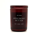A dark amber glass jar candle with a matching lid, featuring white text that reads 'DW HOME APPLE HONEY BUTTER' and 'APPLE | CARAMEL | NUTMEG' on a clean white background.