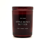 A dark amber glass jar candle with a matching lid, featuring white text that reads 'DW HOME APPLE HONEY BUTTER' and 'APPLE | CARAMEL | NUTMEG' on a clean white background.
