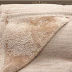 Close-up of a beige knit blanket with a soft plush sherpa lining, folded over to show the texture.