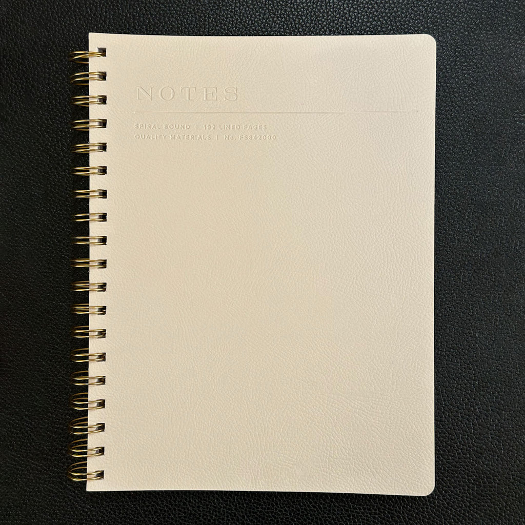 Fringe Studio beige notebook with gold spiral binding on a black background
