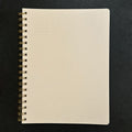 Fringe Studio beige notebook with gold spiral binding on a black background