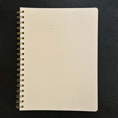 Fringe Studio beige notebook with gold spiral binding on a black background