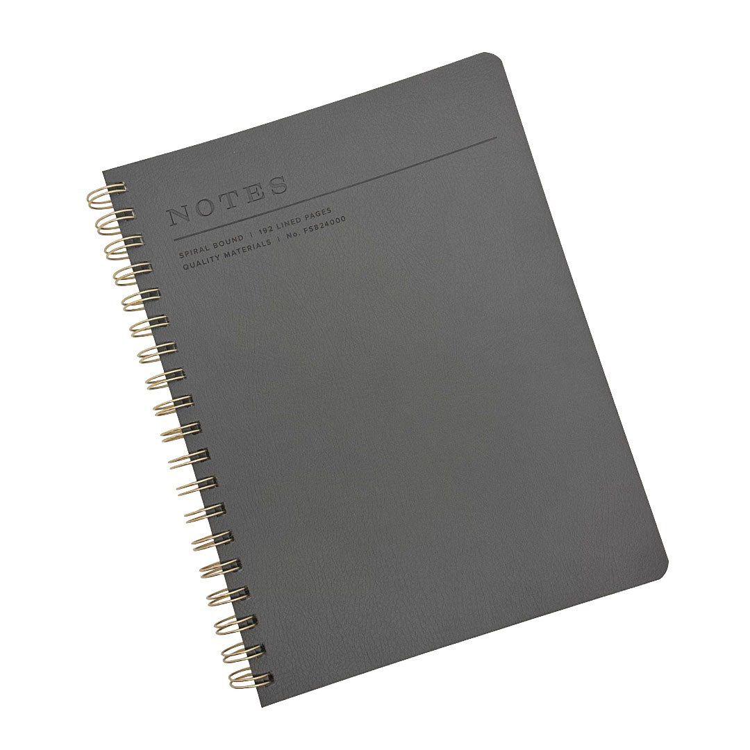 A Fringe Studio charcoal grey textured spiral-bound notebook with gold-toned wire binding and embossed 'NOTES' text on the cover, shown on a plain white background.