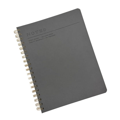 A Fringe Studio charcoal grey textured spiral-bound notebook with gold-toned wire binding and embossed 'NOTES' text on the cover, shown on a plain white background.