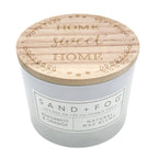 Bergamot & Orange candle with wooden lid featuring 'Home Sweet Home' text, brand 'Sand + Fog' visible.