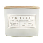 Bergamot & Orange White candle with a wooden lid labeled 'Sand + Fog' on a white background