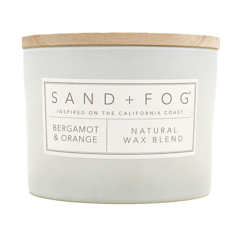 Bergamot & Orange White candle with a wooden lid labeled 'Sand + Fog' on a white background