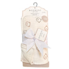 A packaged Bonbini New York muslin and cotton blanket set, featuring a soft cream-colored blanket with a light brown teddy bear pattern, wrapped in a white satin ribbon with a hanging card and a decorative bow.