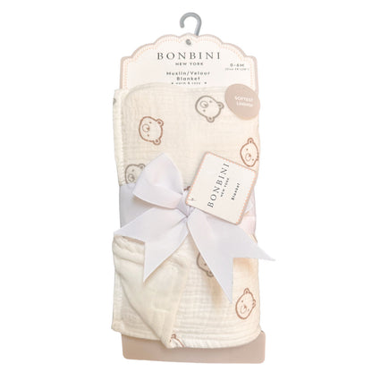A packaged Bonbini New York muslin and cotton blanket set, featuring a soft cream-colored blanket with a light brown teddy bear pattern, wrapped in a white satin ribbon with a hanging card and a decorative bow.