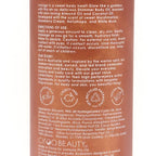 Close-up of the back of a Ciqa Beauty body oil bottle, showing product instructions, ingredients, and certification logos on a warm pinkish-brown background.