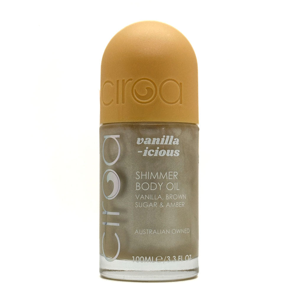 A bottle of Ciroa Vanilla-icious Shimmer Body Oil, featuring a warm golden-brown cap and a shimmering brown body, set against a plain white background.