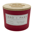 California Beach House red candle with wooden lid labeled 'Sand + Paws' on a white background
