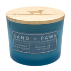 California Beach House Bbue candle with wooden lid labeled 'Sand + Paws' on a white background