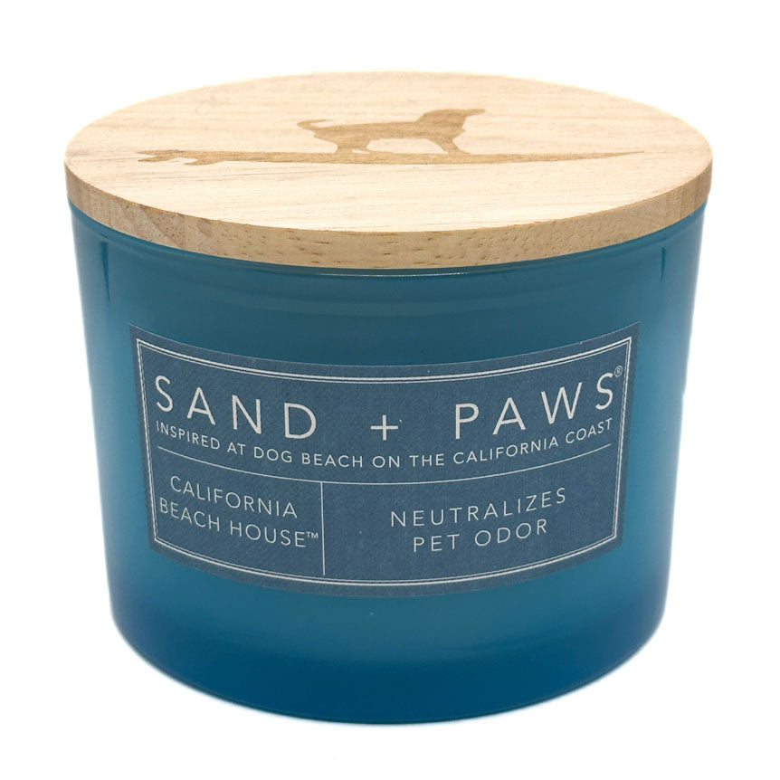 California Beach House Bbue candle with wooden lid labeled 'Sand + Paws' on a white background